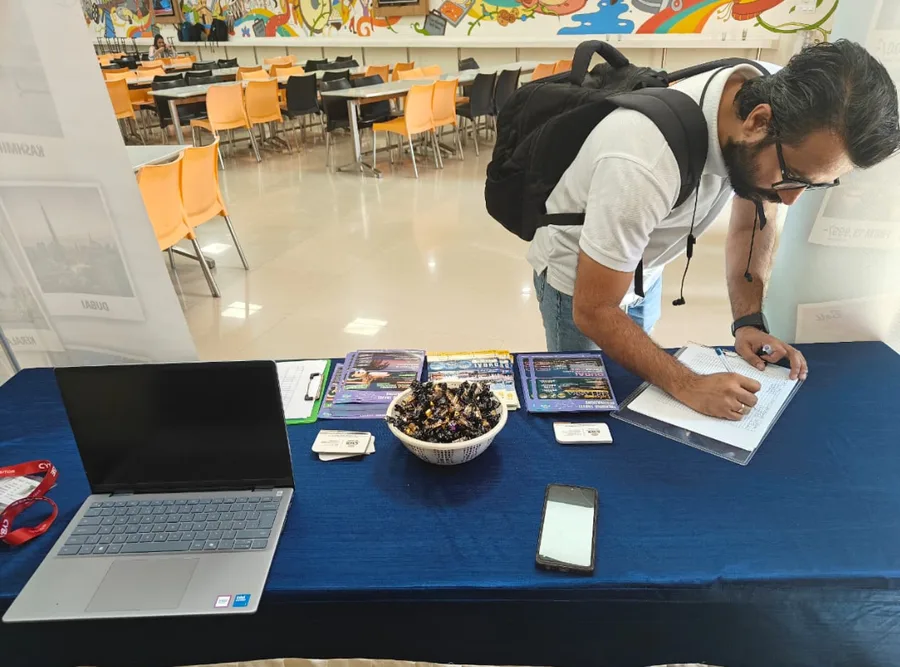 A CWS colleague writing at a exhibition desk beside a laptop and giveaways