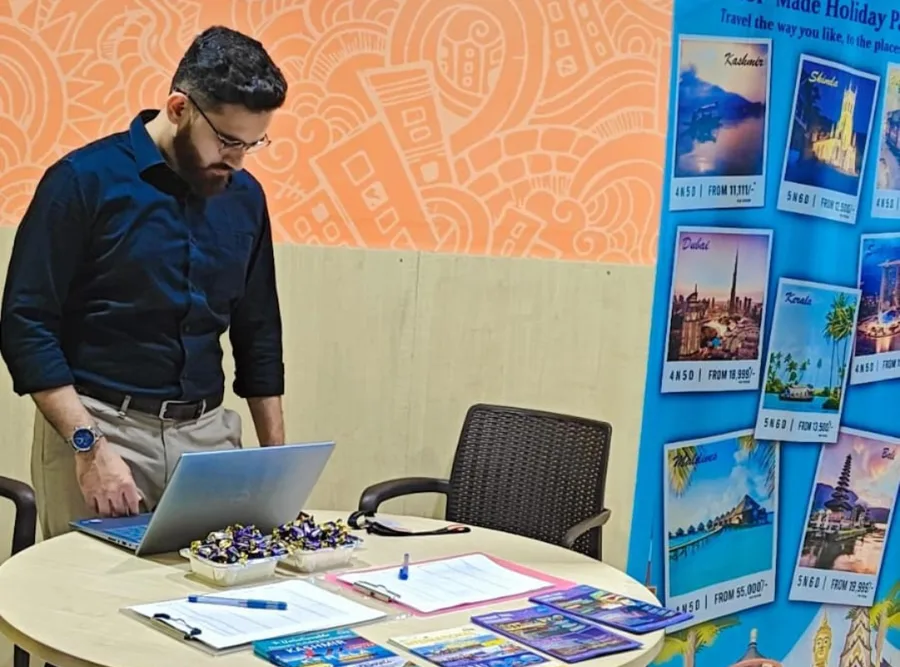 A colleague working at a laptop at the stand desk against an orange wall