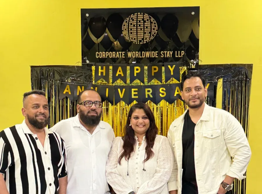 Colleagues in front of a Corporate Worldwide Stay anniversary backdrop