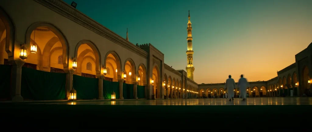 Two pilgrims crossing a mosque courtyard at dusk, lanterns lit along the arcades and a floodlit minaret beyond